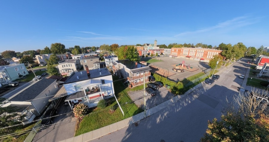 Vue aérienne d'une maison et de son terrain, avec une cour d'école en arrière-plan